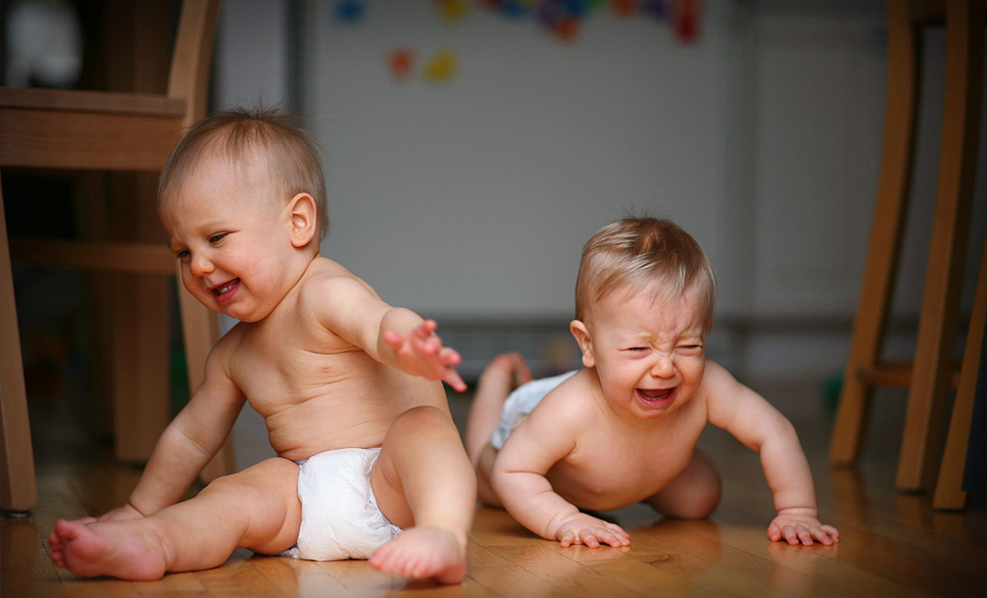 photo of twin babies crying and throwing tantrum on floor in diapers by Heidi Brady